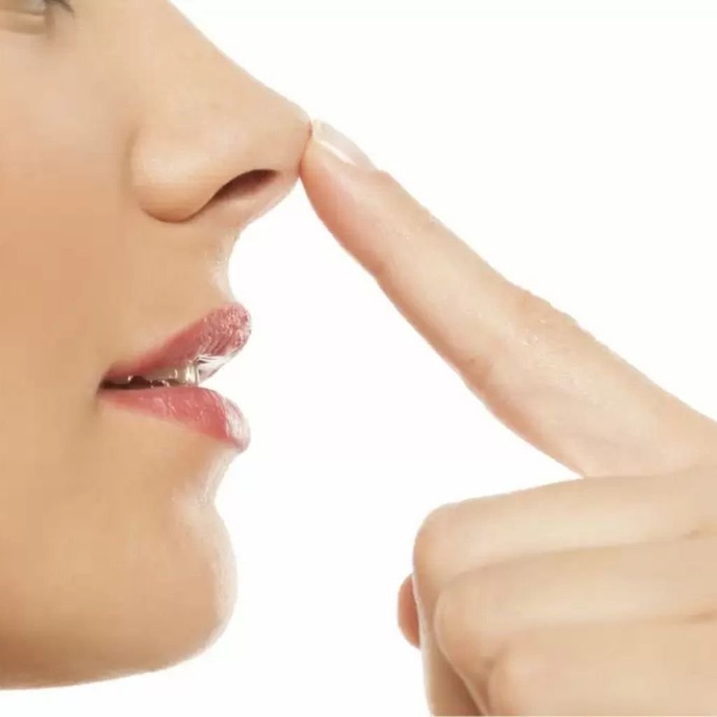 Side profile of a woman gently touching her nasal tip, illustrating structural tip refinement and nose reshaping at Transform Head to Toe Bengaluru.