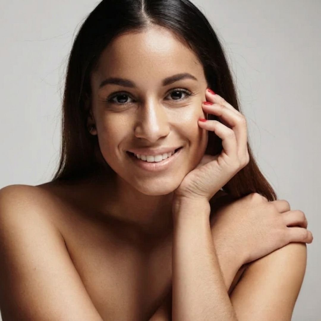 Smiling woman with clear skin and manicured nails - Advanced Skincare and Aesthetics Transform Head to Toe